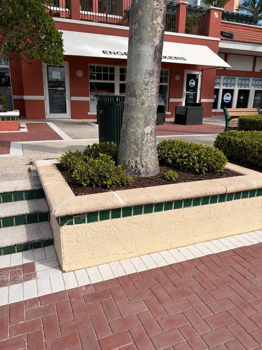 348 S Us Highway 1, #44, Jupiter, Jupiter, FL 33477 Stucco planter with green tile accents and stone cap, herringbone-patterned brick paver walkway, and built-in masonry steps