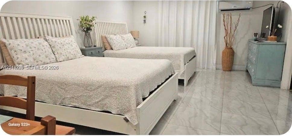 144 NW 7th Avenue, #2, Dania, Dania Beach, FL 33004 Neutral-toned room featuring large-format stone-finish tile flooring, wall-mounted climate control unit, and floor-to-ceiling drapery