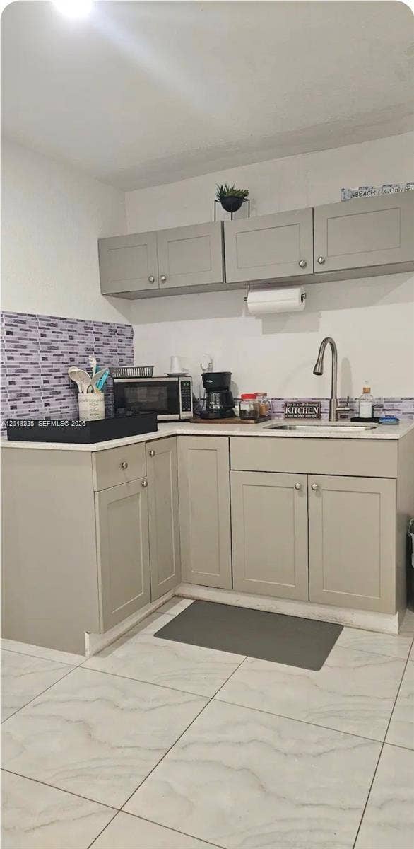 144 NW 7th Avenue, #2, Dania, Dania Beach, FL 33004 Kitchenette featuring light-toned shaker-style cabinetry, a stone-composite countertop, a high-arc faucet with an undermount sink, a mosaic-tiled backsplash, and large-format porcelain tile flooring