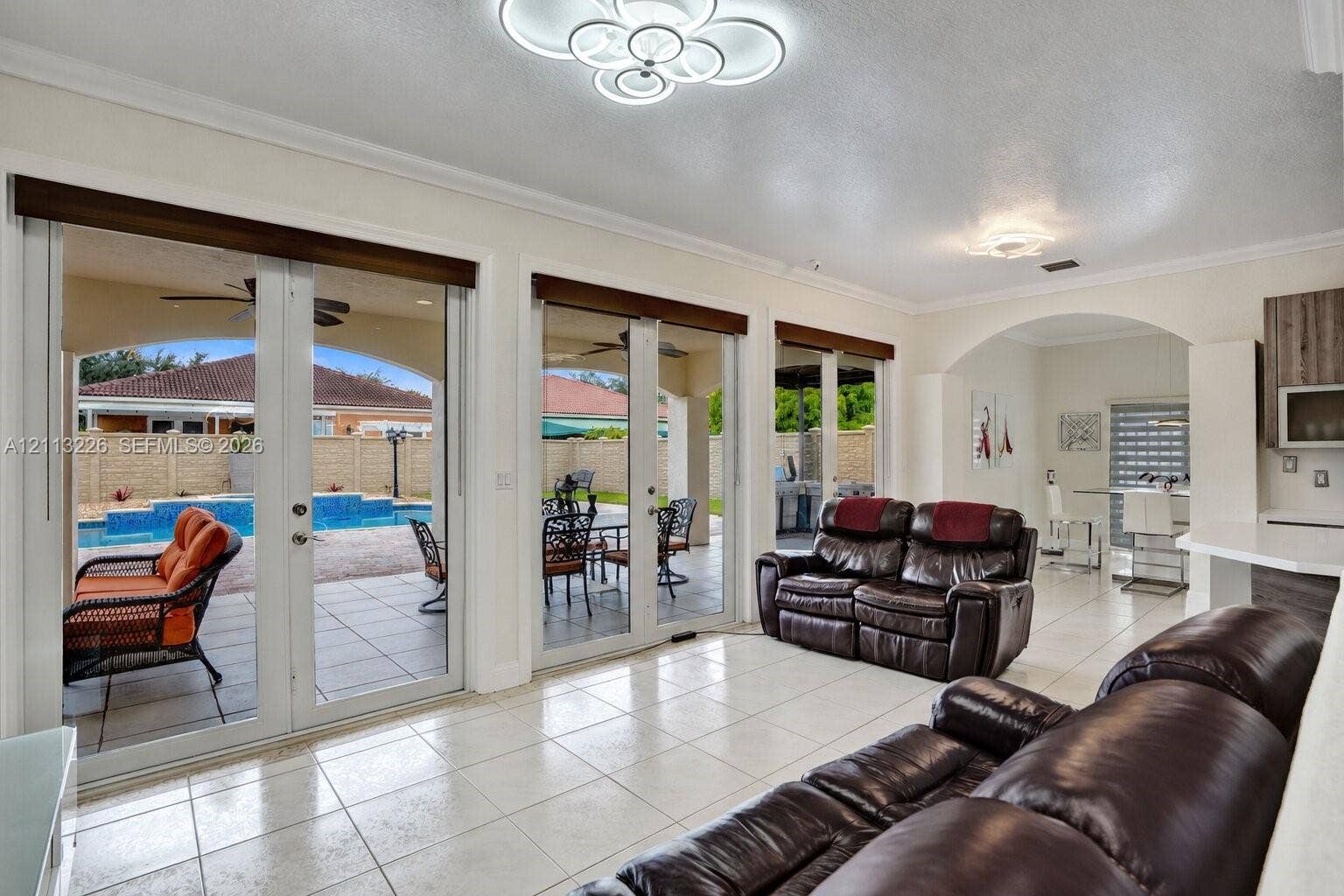 Main living area featuring tile flooring, multi-panel glass French doors, architectural archway, and geometric LED ceiling lighting