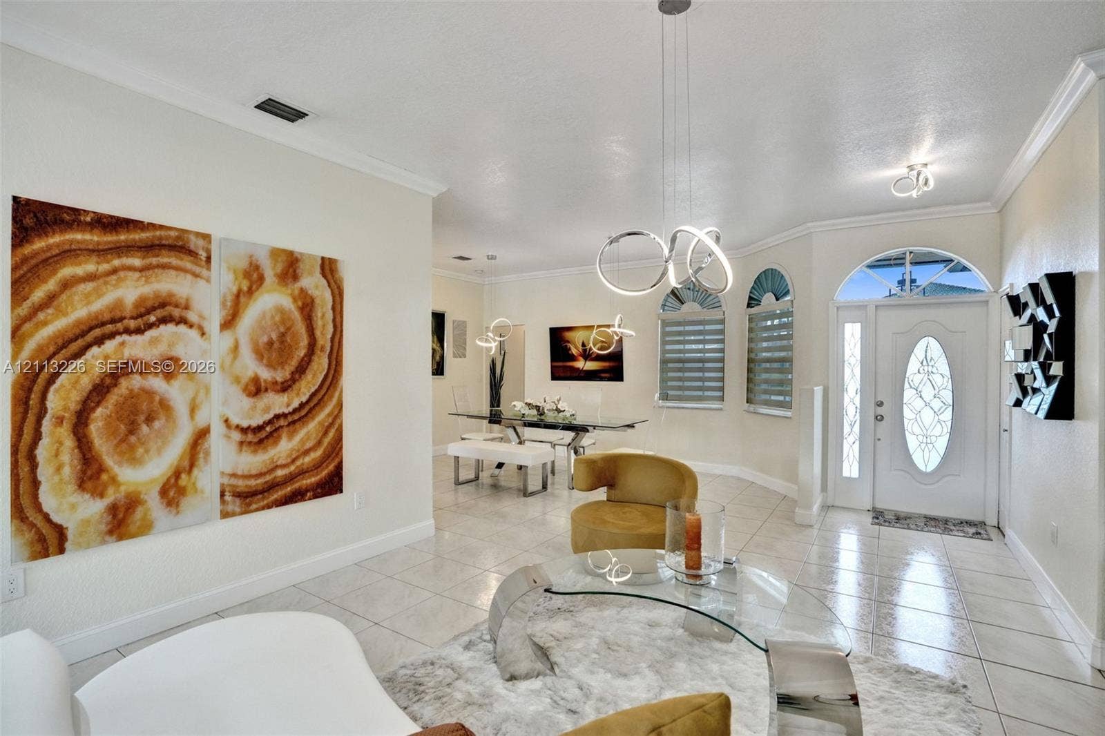 Entryway featuring tile flooring, arched windows, an oval glass-paneled front door, and modern multi-ring pendant lighting