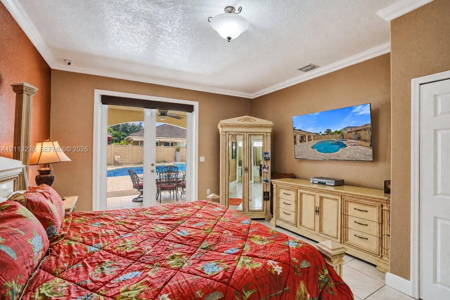 Room featuring crown molding, recessed lighting, tile flooring, and glass-paned double doors leading to a patio with a swimming pool