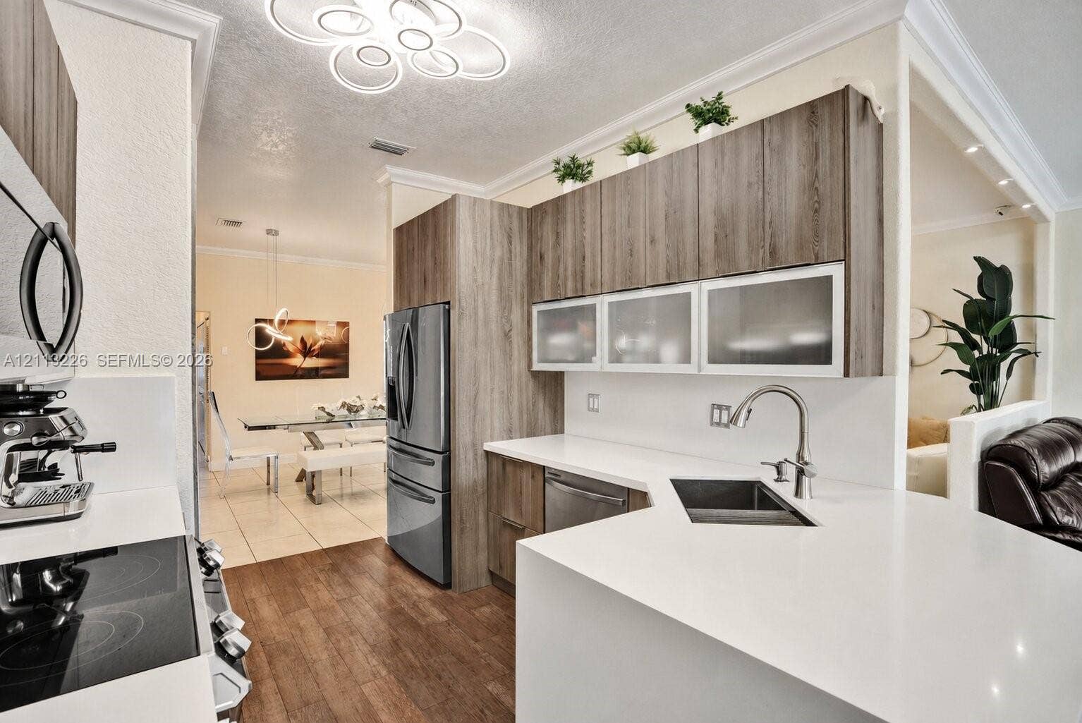 Kitchen featuring light wood-finish cabinetry, white countertops, a stainless steel undermount sink with a gooseneck faucet, and recessed ceiling lighting