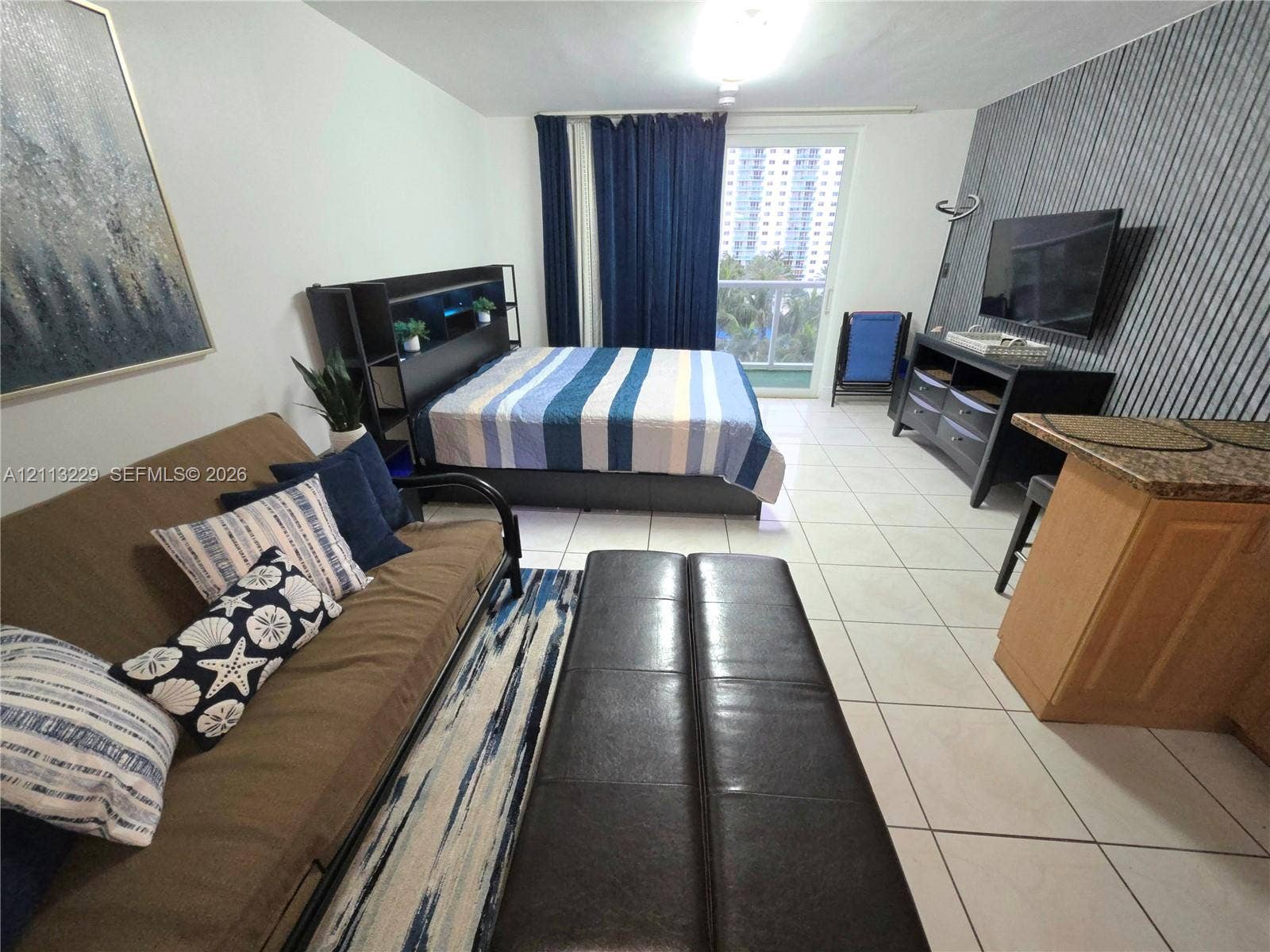 Ceramic tile flooring, textured accent wall, and sliding glass door with balcony access