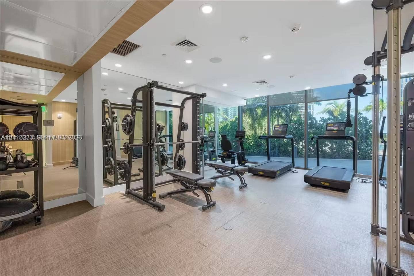 Fitness facility featuring floor-to-ceiling windows, full-wall mirrors, recessed lighting, and synthetic flooring