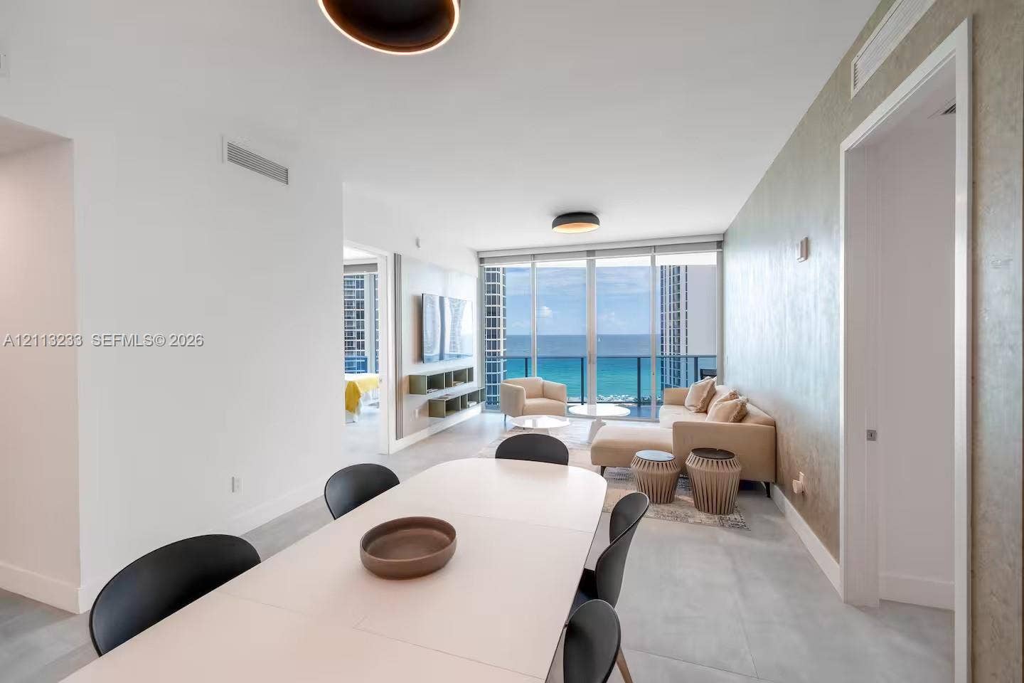 Open-concept interior featuring floor-to-ceiling glass, wall-mounted cabinetry, textured accent wall, and porcelain tile flooring