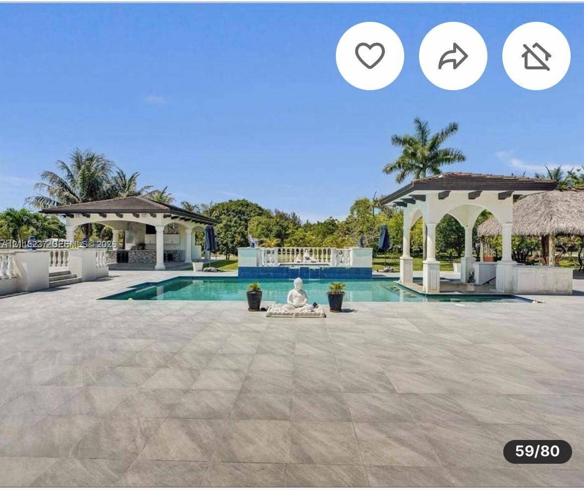12401 SW 45th Street, Miami, FL 33175 Extensive patio area with large-format tile flooring, rectangular pool, dual covered structures with architectural columns, and a tiered fountain feature