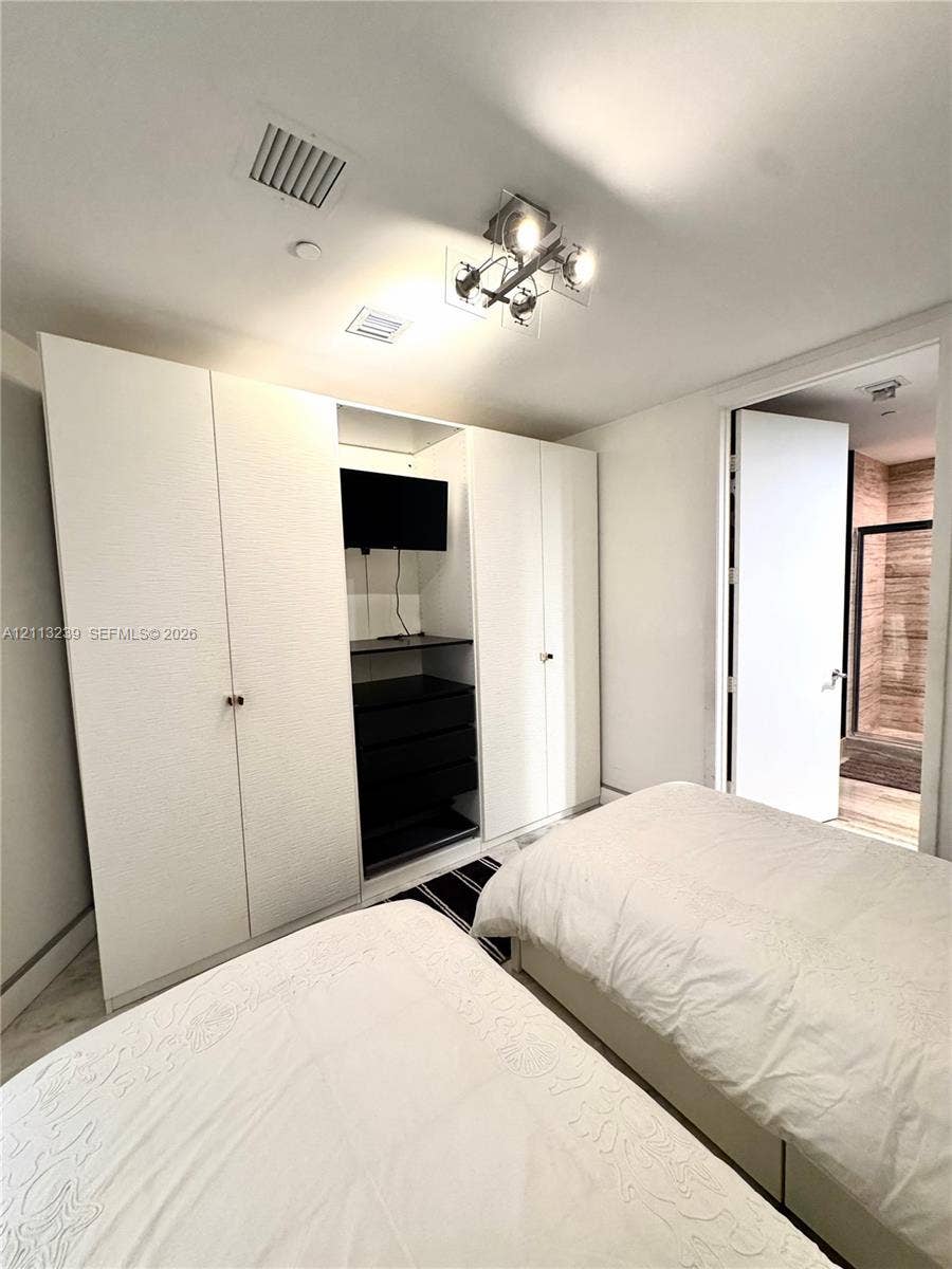 16001 Collins Avenue, #2403, Sunny Isles Beach, Sunny Isles Beach, FL 33160 Built-in white cabinetry with integrated shelving and drawers, four-light modern ceiling fixture, and stone-finish flooring