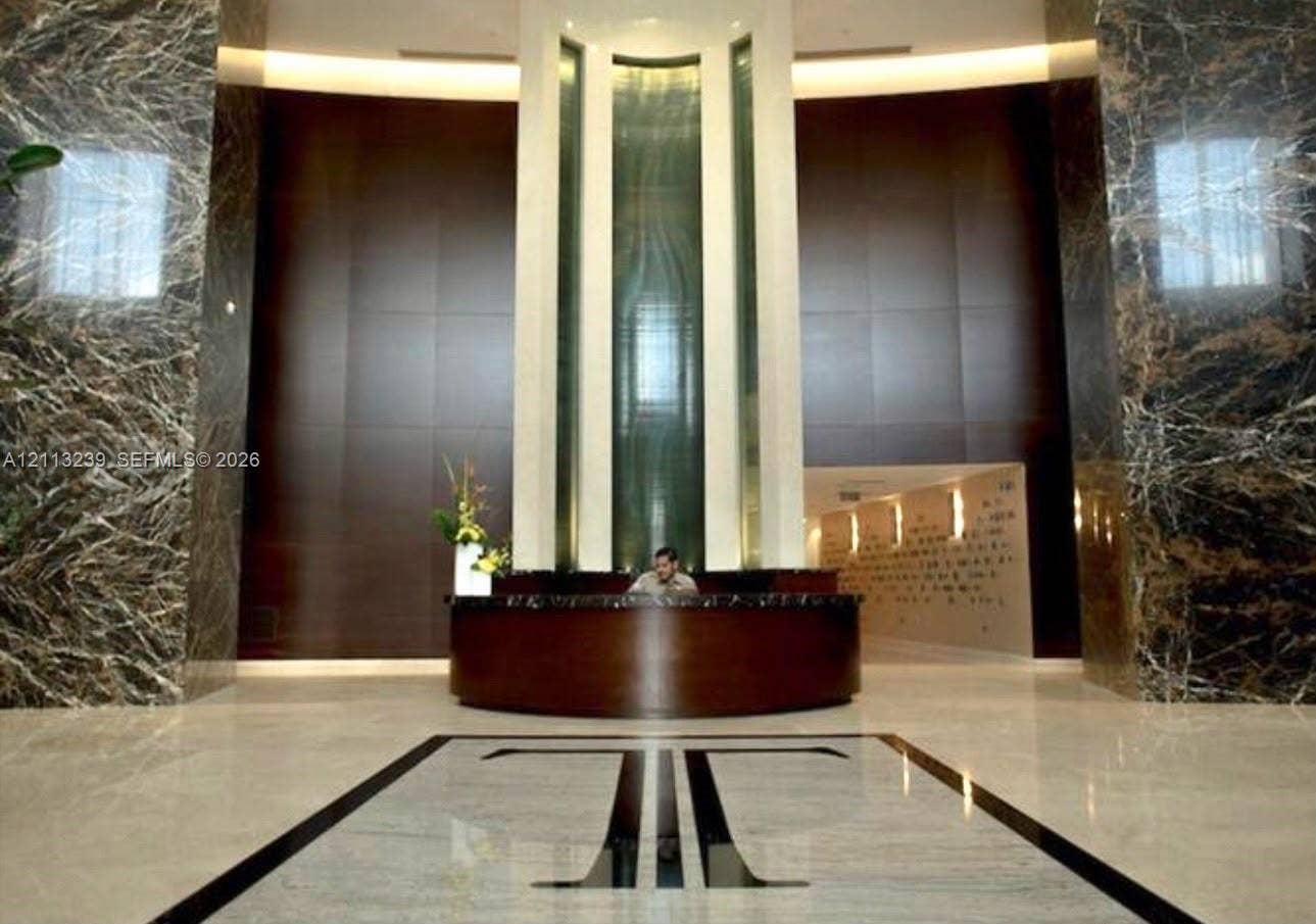 16001 Collins Avenue, #2403, Sunny Isles Beach, Sunny Isles Beach, FL 33160 Grand entrance featuring floor-to-ceiling stone wall cladding, polished stone flooring with geometric inlay, and a built-in concierge desk