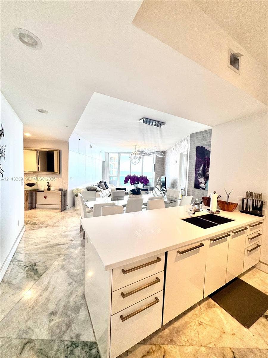 16001 Collins Avenue, #2403, Sunny Isles Beach, Sunny Isles Beach, FL 33160 Kitchen island featuring white high-gloss cabinetry, a solid surface countertop, and an integrated undermount sink with a matte finish