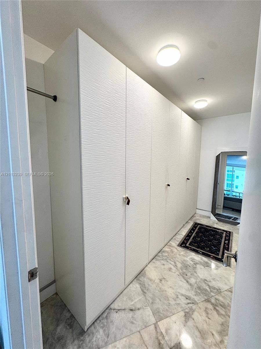 16001 Collins Avenue, #2403, Sunny Isles Beach, Sunny Isles Beach, FL 33160 Full-height white built-in cabinetry with textured fronts, stone-finish flooring, and recessed ceiling lighting