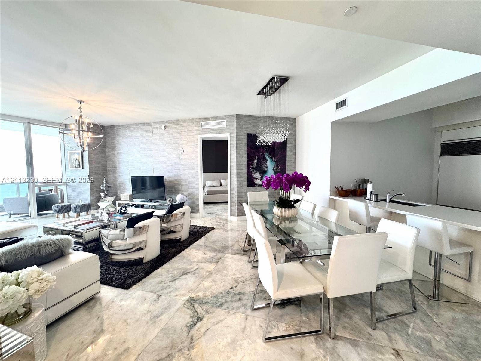 16001 Collins Avenue, #2403, Sunny Isles Beach, Sunny Isles Beach, FL 33160 Open-concept living space featuring large-format polished stone flooring, textured wall coverings, floor-to-ceiling windows, and a breakfast bar with stone surfacing