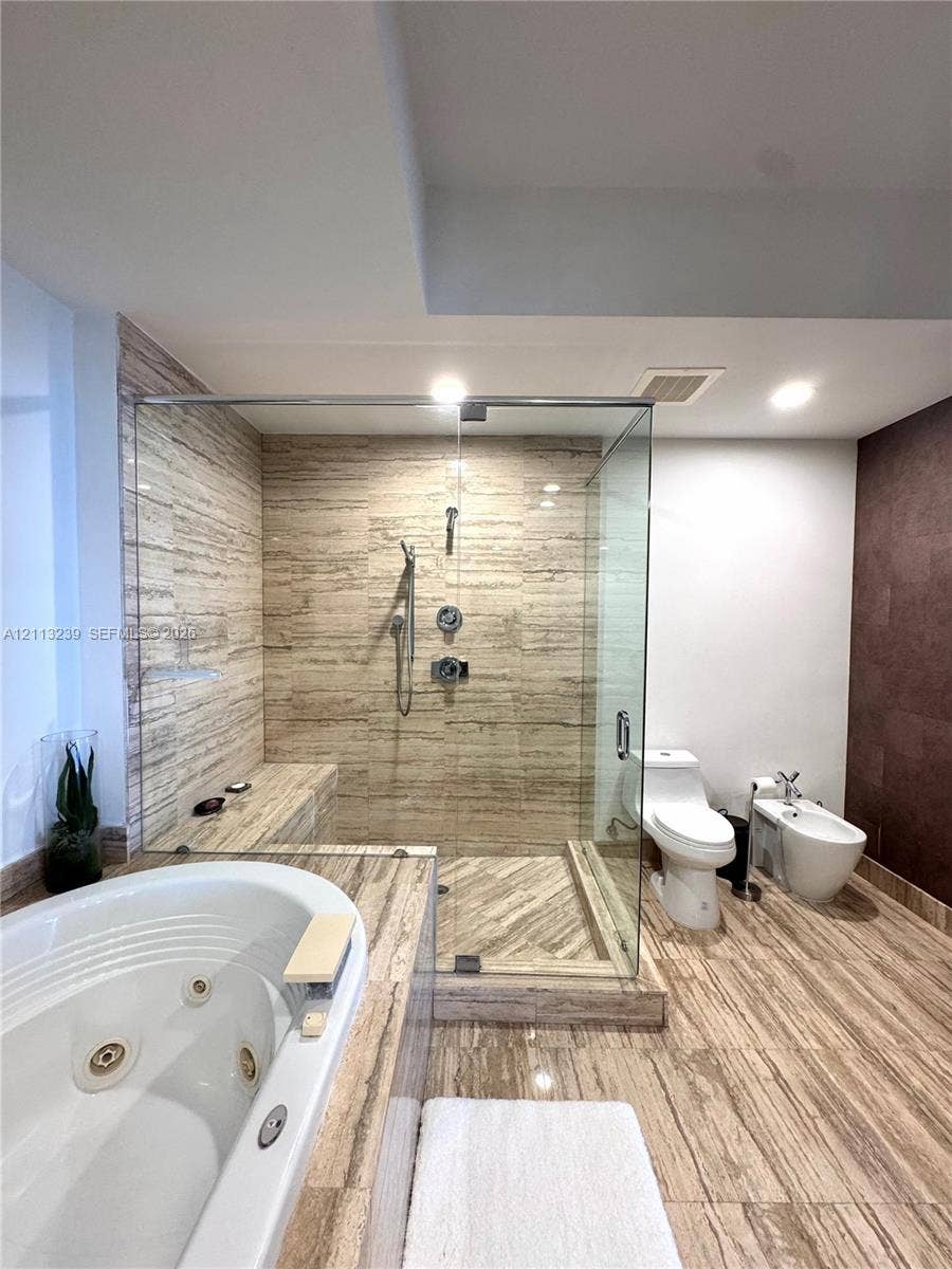 16001 Collins Avenue, #2403, Sunny Isles Beach, Sunny Isles Beach, FL 33160 Full-size jetted soaking tub, walk-in shower with stone-tile surround, built-in shower bench, and stone-tile flooring