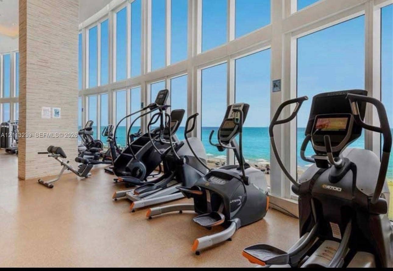 16001 Collins Avenue, #2403, Sunny Isles Beach, Sunny Isles Beach, FL 33160 Fitness center featuring floor-to-ceiling windows, a stacked stone column, and neutral flooring