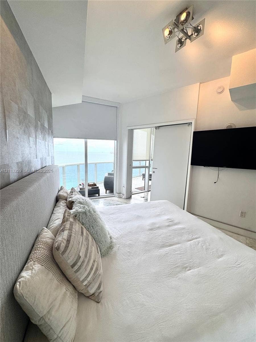 16001 Collins Avenue, #2403, Sunny Isles Beach, Sunny Isles Beach, FL 33160 Textured feature wall with metallic finish, floor-to-ceiling glass sliding door, balcony access, and geometric ceiling-mounted light fixture