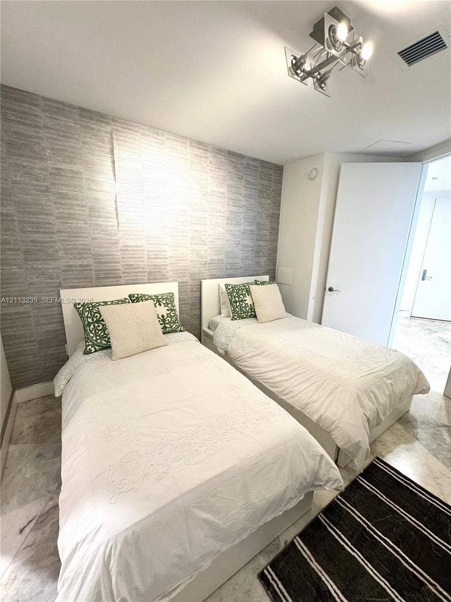 16001 Collins Avenue, #2403, Sunny Isles Beach, Sunny Isles Beach, FL 33160 Bedroom featuring stone flooring, textured wall covering, and a multi-directional track lighting fixture