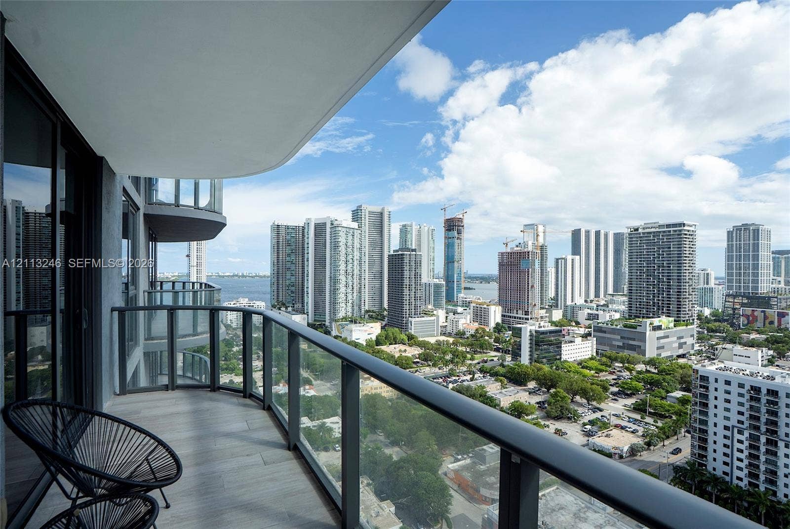 121 NE 34th Street, #2703, Miami, FL 33137 Private balcony featuring wood-finish flooring, glass panel railings, and expansive urban skyline scenery