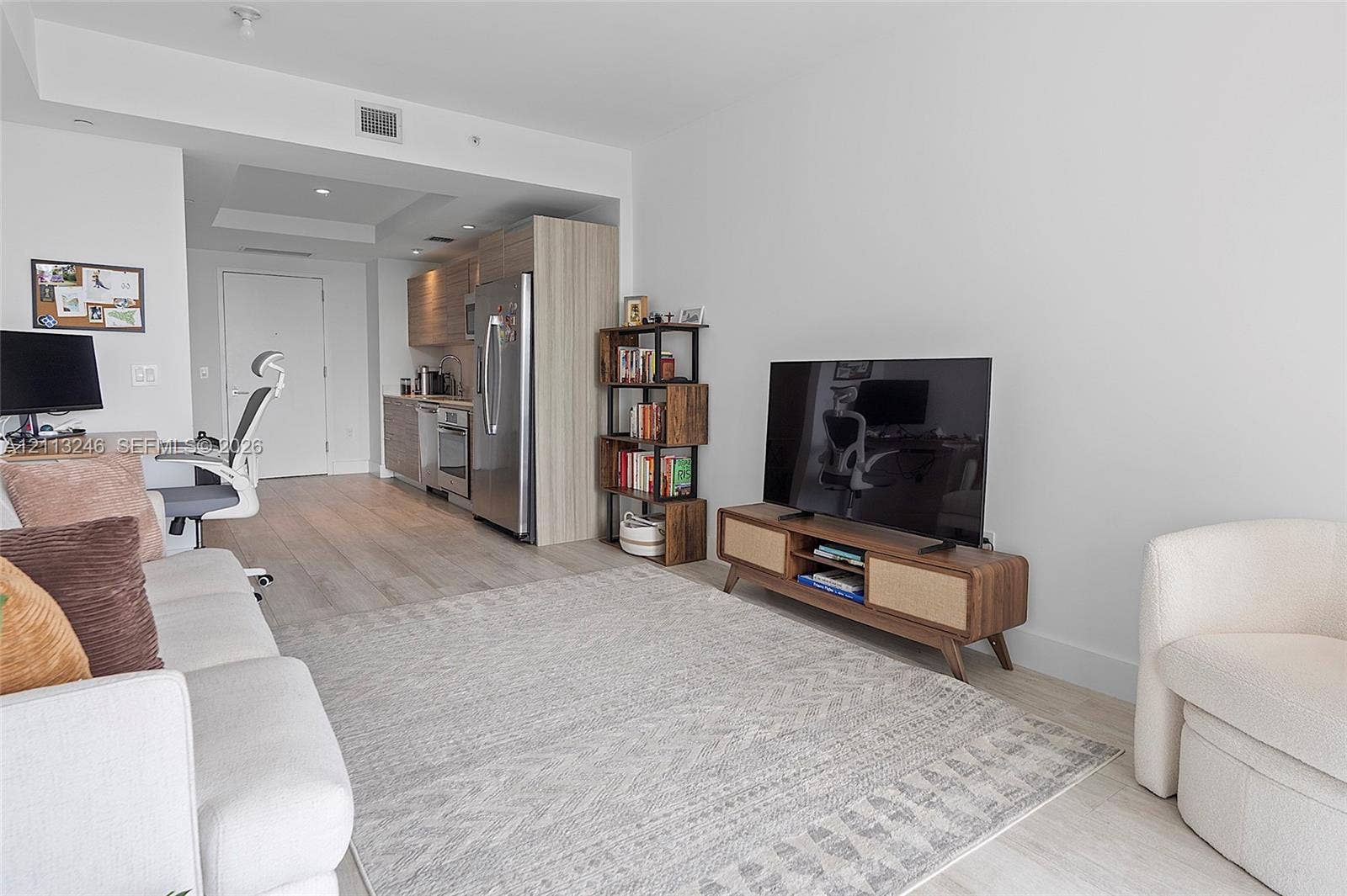 121 NE 34th Street, #2703, Miami, FL 33137 Open-concept living space featuring wood-finish flooring, recessed lighting, and a kitchen equipped with stainless steel appliances and wood-grain cabinetry