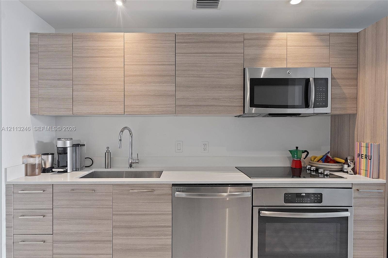 121 NE 34th Street, #2703, Miami, FL 33137 Kitchen featuring wood-finish cabinetry, quartz countertops, stainless steel appliances, and a gooseneck faucet