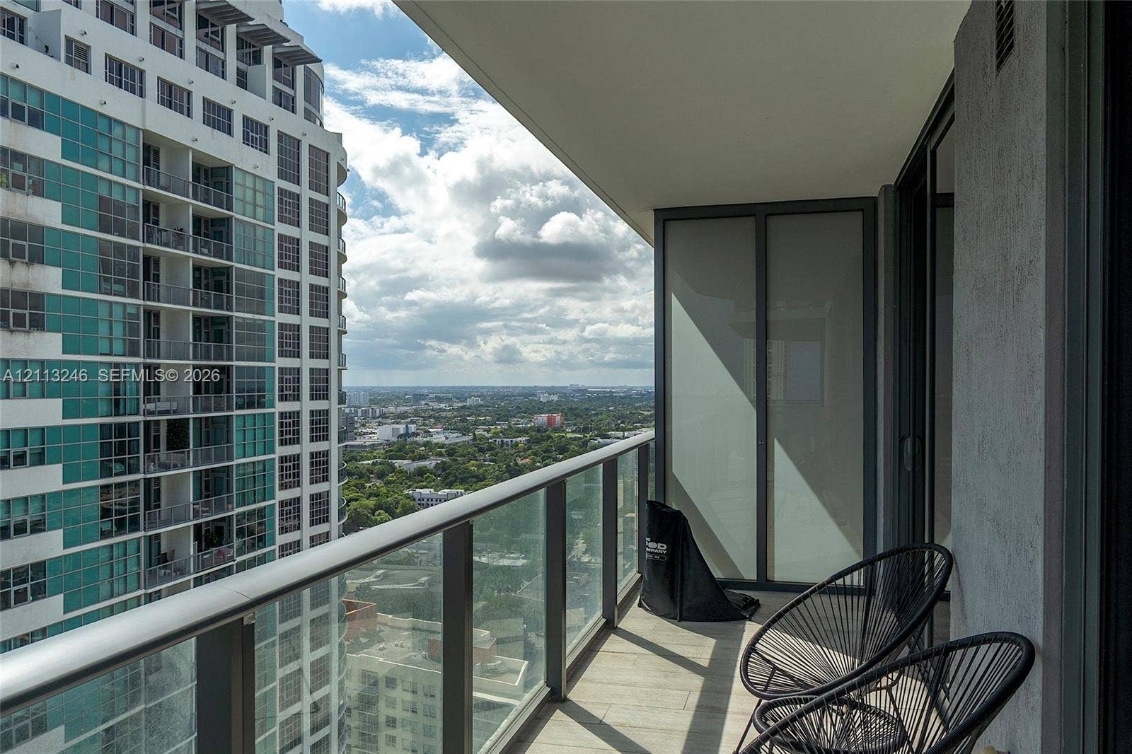 121 NE 34th Street, #2703, Miami, FL 33137 Covered balcony featuring a glass panel railing, tile flooring, and frosted privacy screen