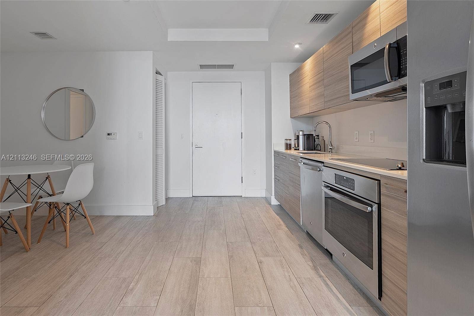 121 NE 34th Street, #2703, Miami, FL 33137 Kitchen featuring wood-finish cabinetry, stainless steel appliances, and solid-surface countertops, complemented by wood-finish flooring