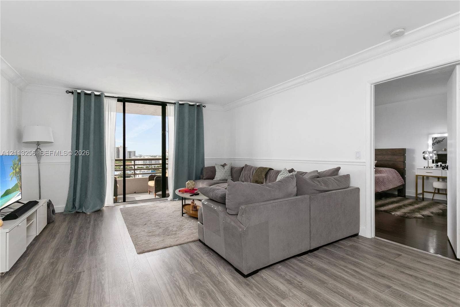3300 NE 191st Street, #1514, Aventura, FL 33180 Living space featuring wood-finish flooring, crown molding, chair rail trim, and sliding glass doors opening to a balcony