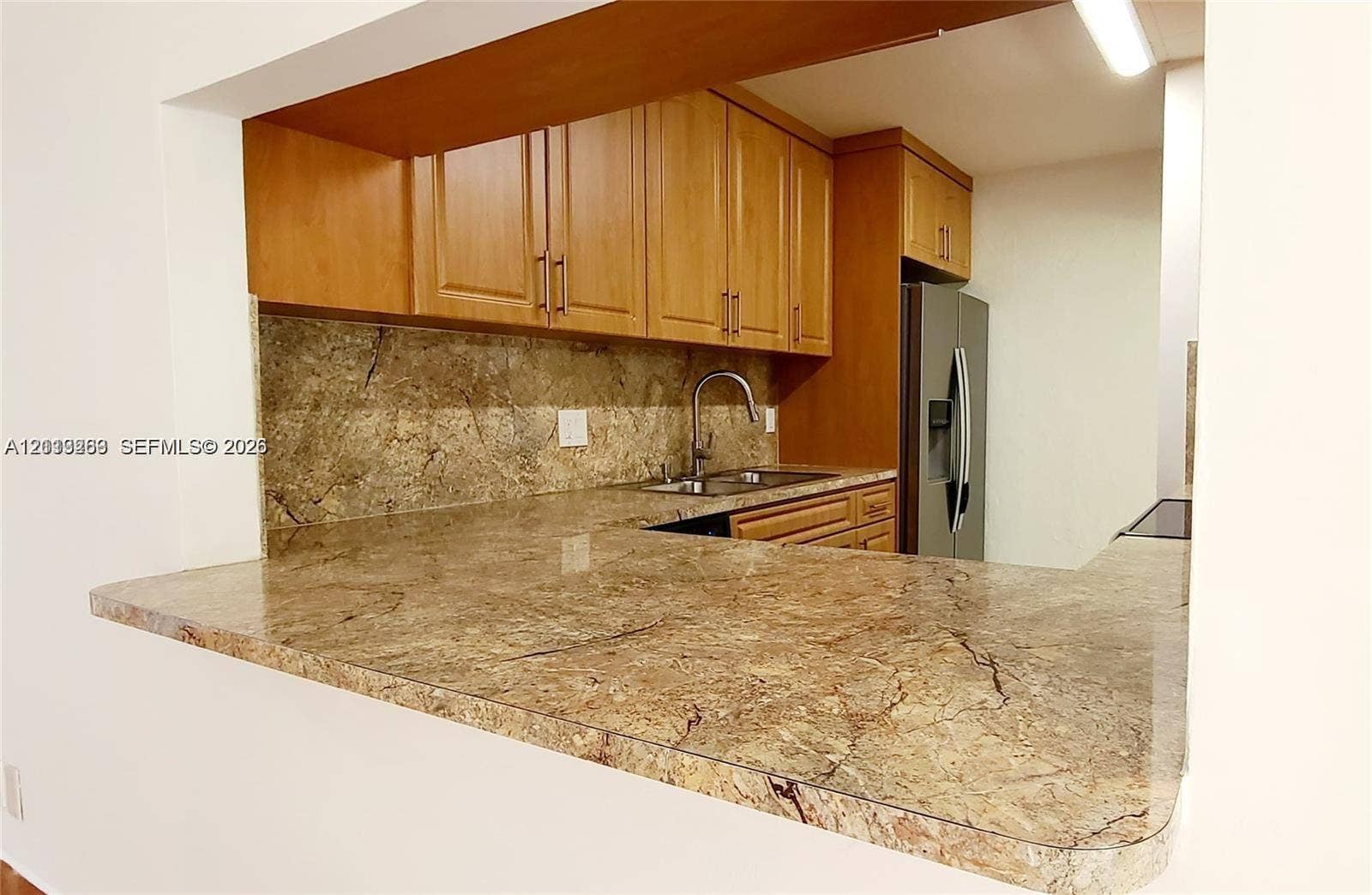 9410 Live Oak Place, #109, Davie, Davie, FL 33324 Kitchen featuring wood cabinetry, stone countertops, stone backsplash, stainless steel sink with gooseneck faucet, and stainless steel refrigerator