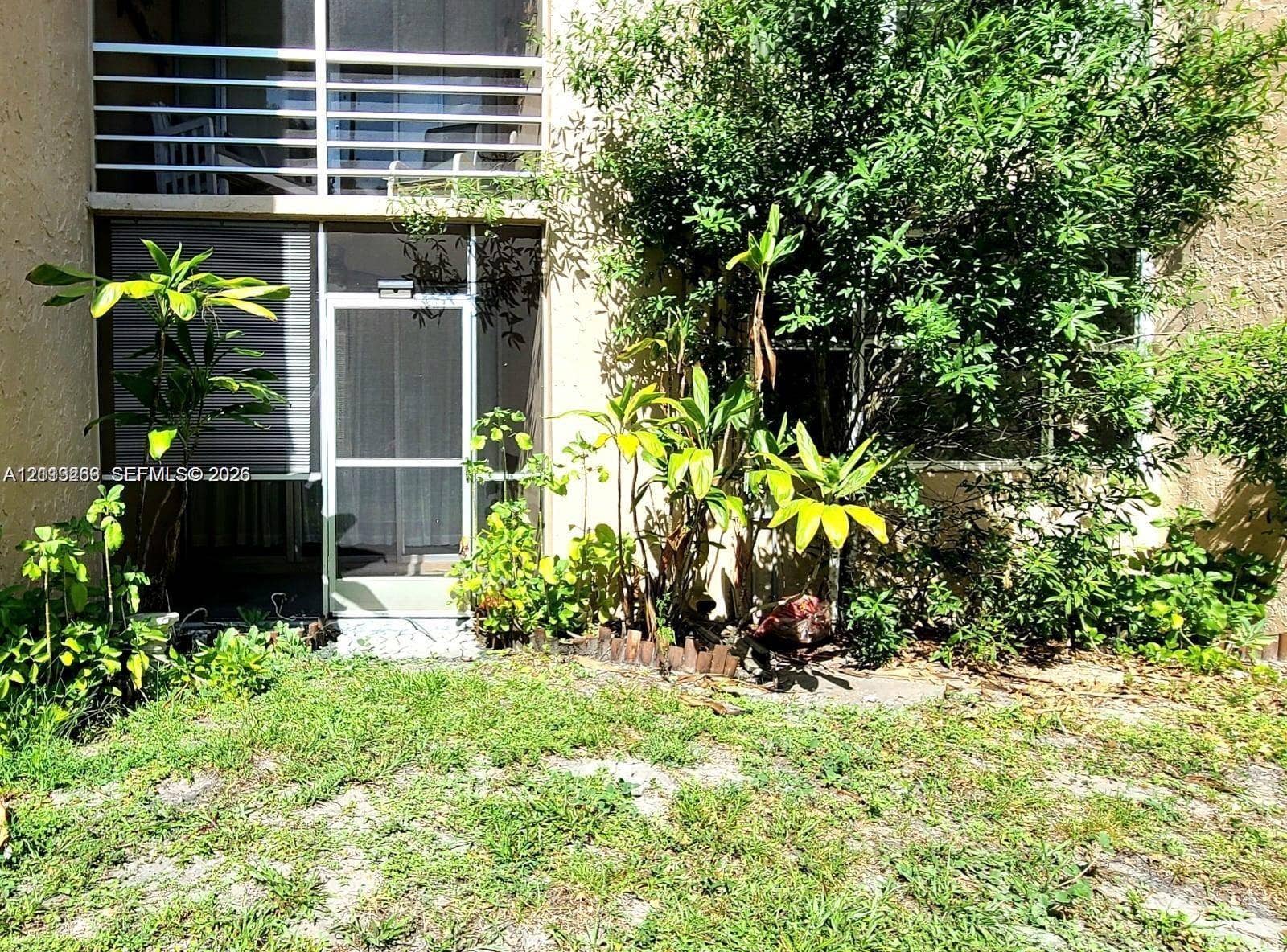 9410 Live Oak Place, #109, Davie, Davie, FL 33324 Screened patio enclosure featuring a metal-framed door and upper balcony railing
