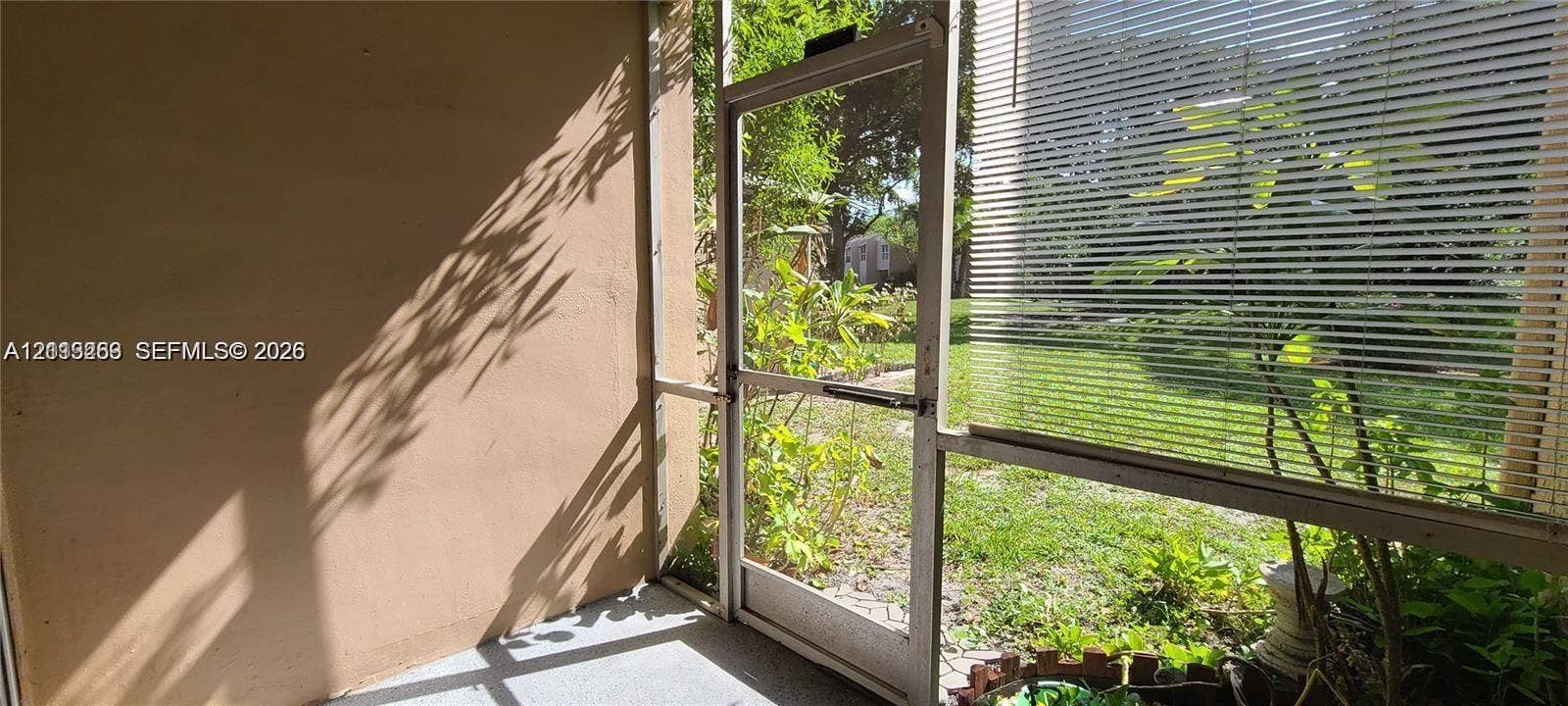 9410 Live Oak Place, #109, Davie, Davie, FL 33324 Enclosed patio featuring a concrete floor, solid wall construction, and a screen door with metal framing