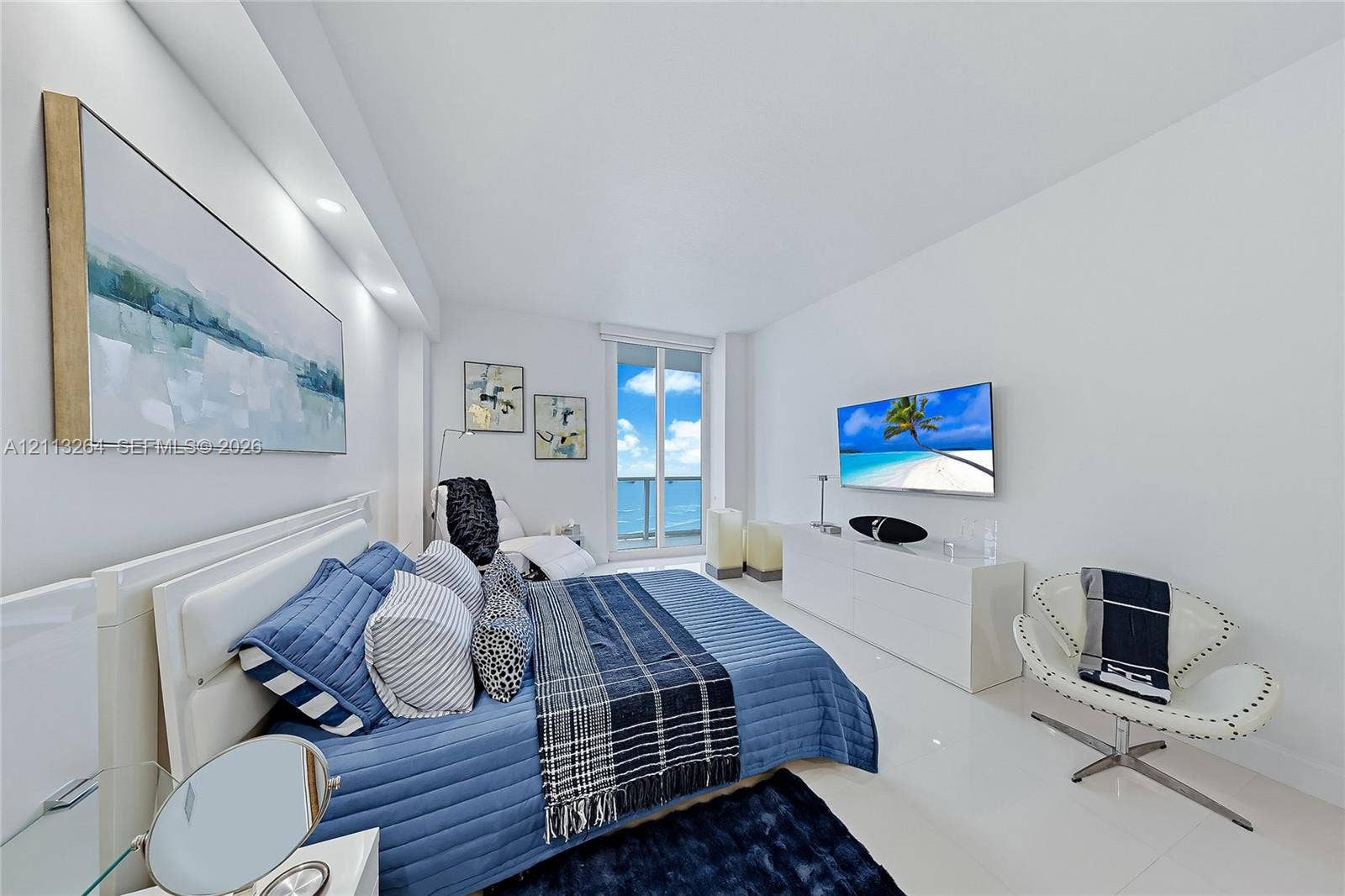 Spacious interior featuring high-gloss tile flooring, recessed ceiling lighting, and a glass-paneled door leading to an outdoor balcony