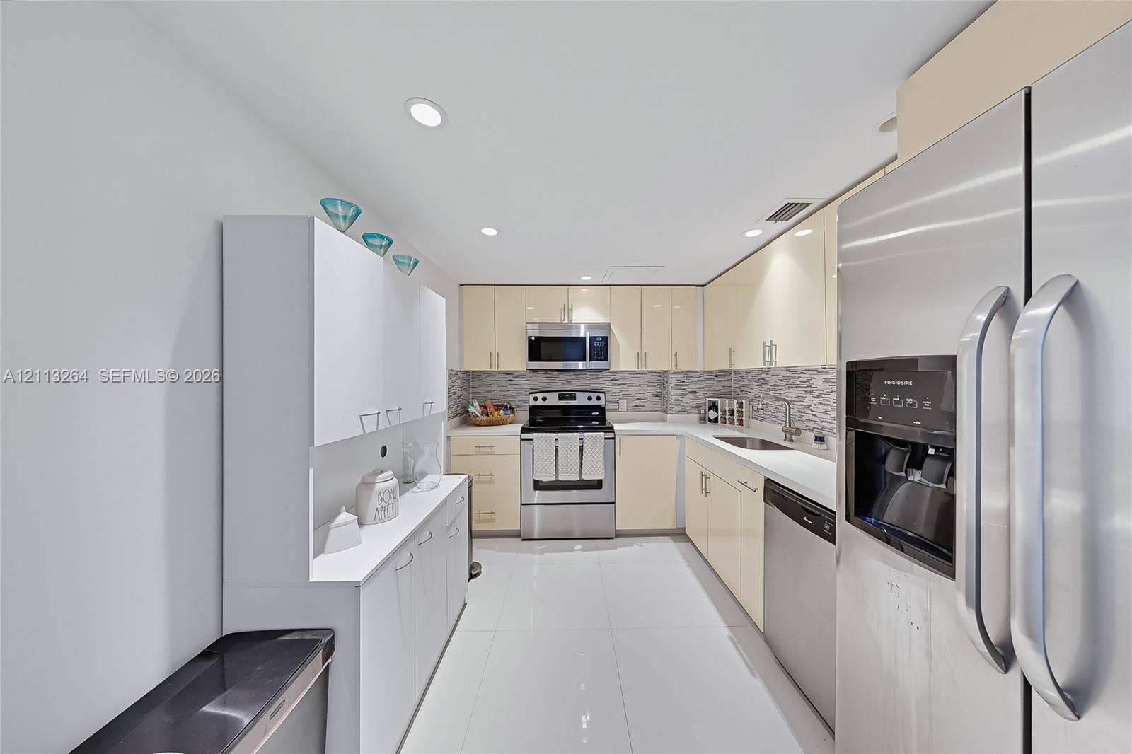 Kitchen featuring glossy cabinetry, stainless steel appliances, tile backsplash, polished stone countertops, and tile flooring
