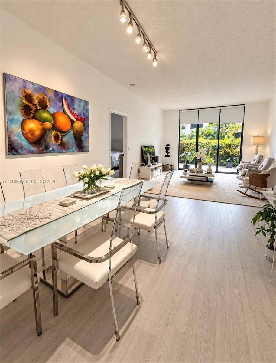 Living area featuring wood-finish flooring, floor-to-ceiling black-framed glass sliding doors, and neutral wall tones