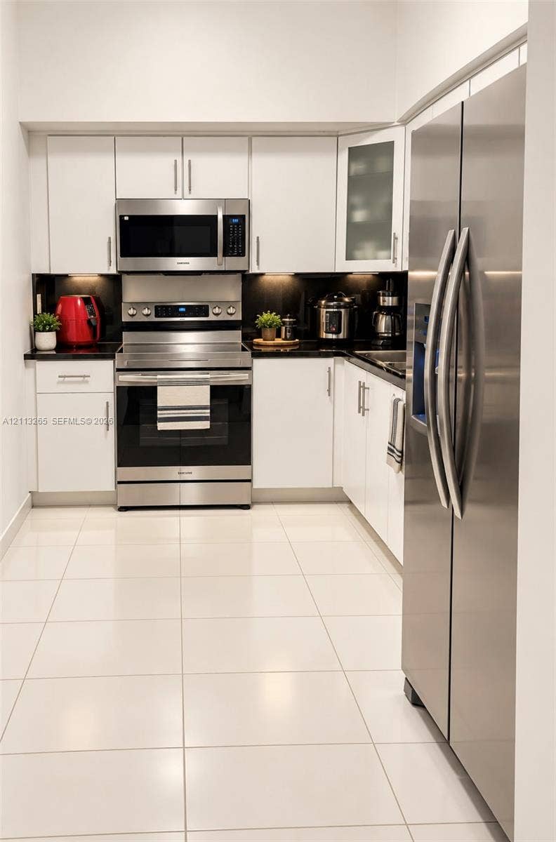 Dual-basin vanity featuring white cabinetry, a neutral countertop, undermount sinks, and a large plate-glass mirror with a multi-bulb light fixture