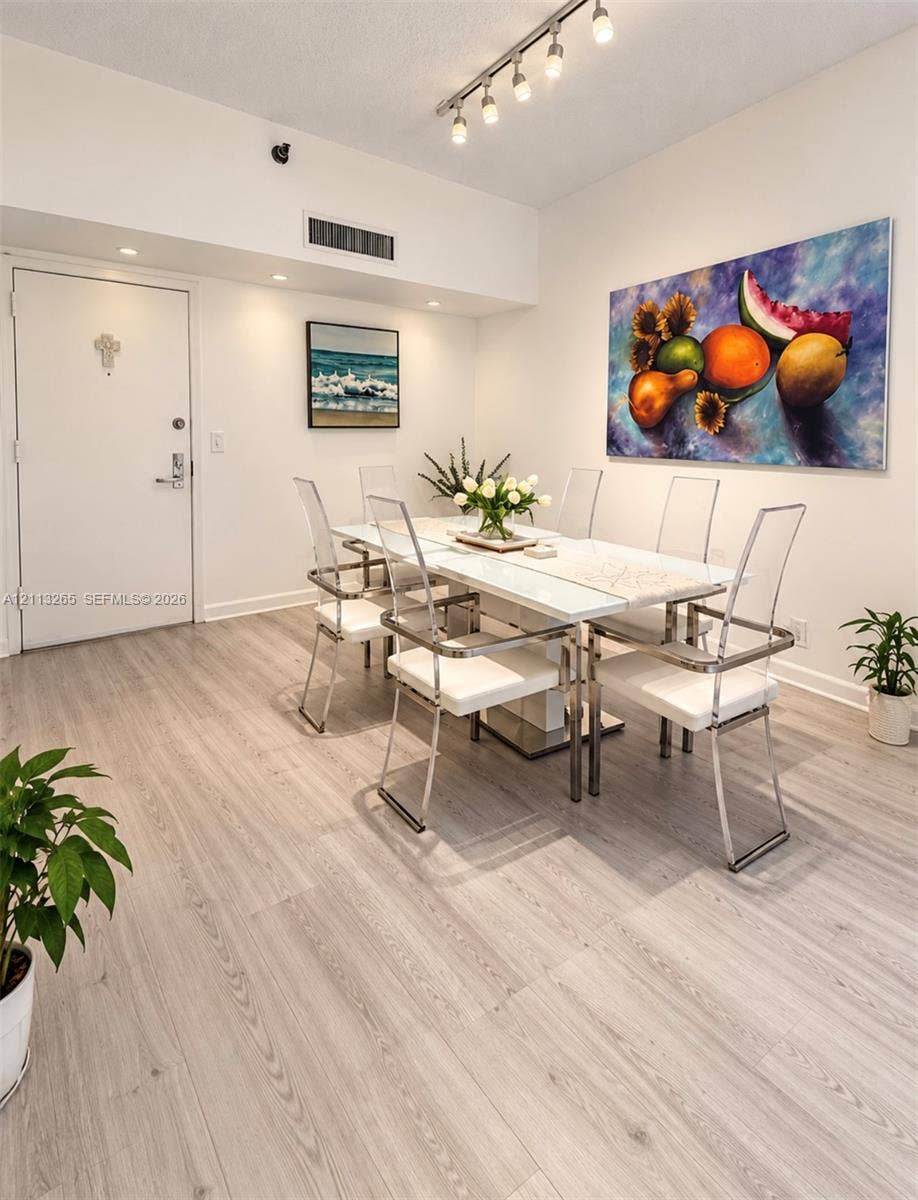 Kitchen featuring white shaker-style cabinetry, dark stone countertops, stainless steel appliances, a glass-front upper cabinet, and light-toned tile flooring