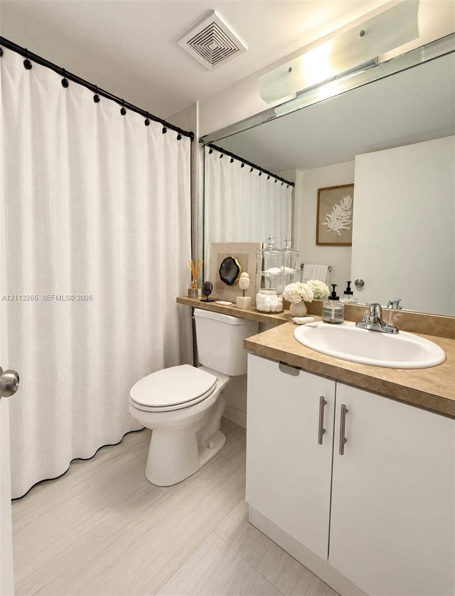 Stackable white laundry unit housed in a closet featuring white louvered doors