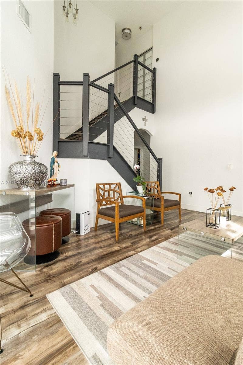 11494 NW 79th Lane, Doral, FL 33178 Staircase featuring dark-finished wooden railings and integrated stainless steel cable balusters, complemented by high-vaulted ceilings and wood-finish flooring