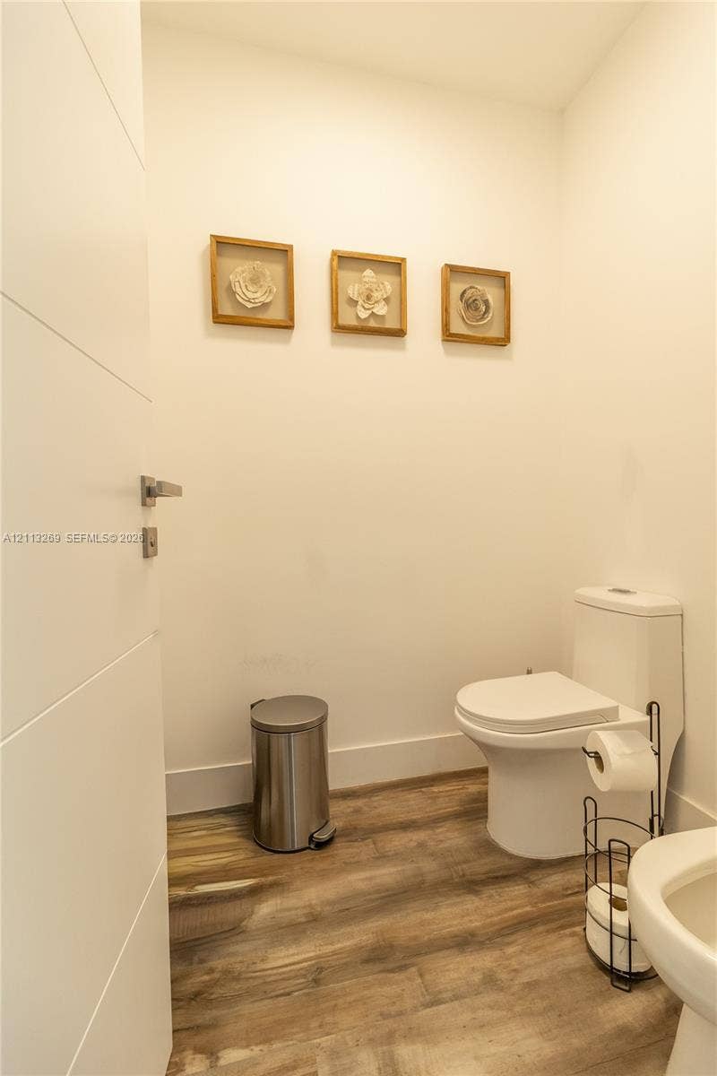 11494 NW 79th Lane, Doral, FL 33178 Wood-finish flooring, dual-flush toilet, and solid-core interior door with satin nickel hardware