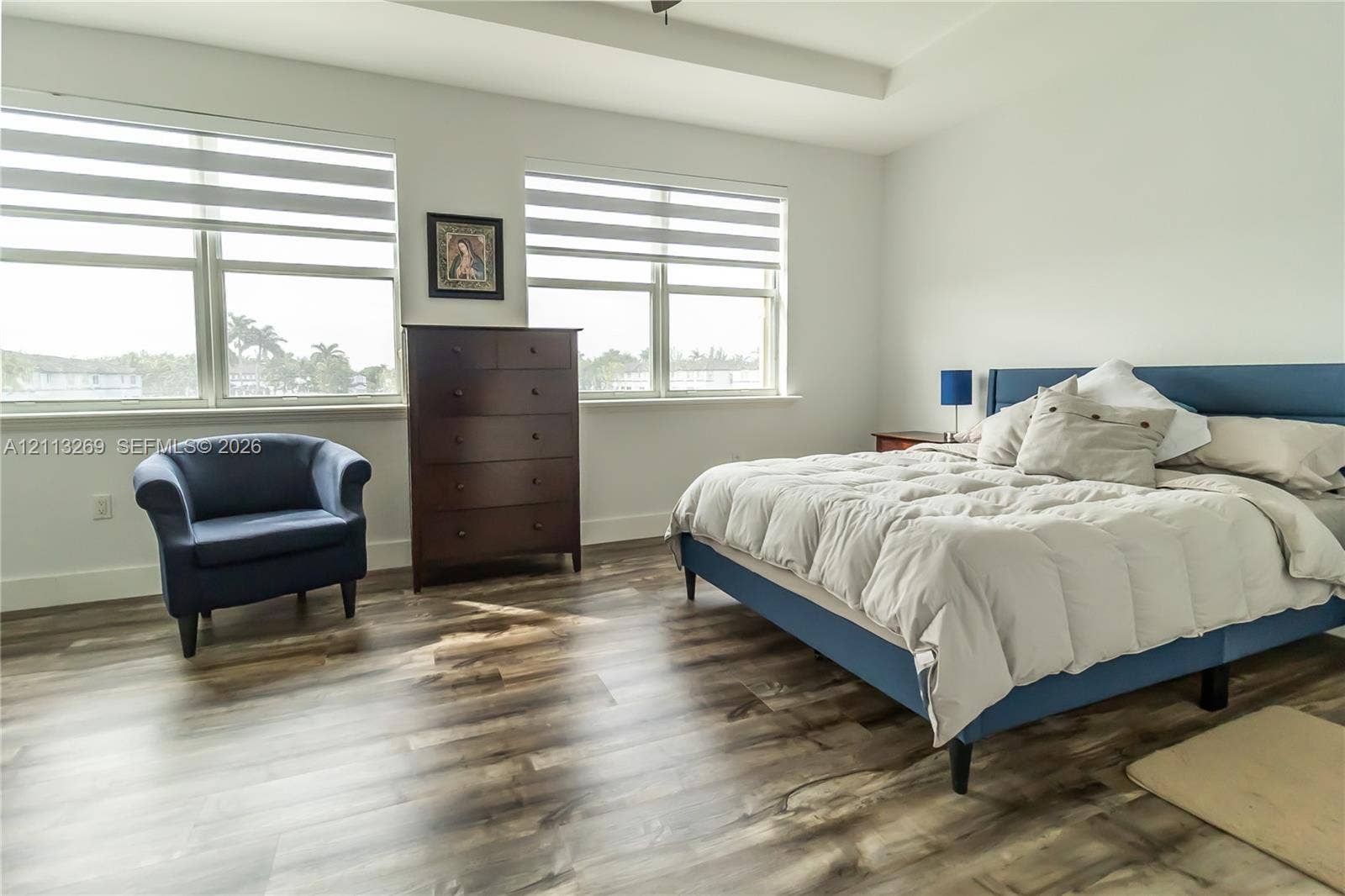 11494 NW 79th Lane, Doral, FL 33178 Room featuring wood-finish flooring, tray ceiling, and dual large windows with horizontal blinds