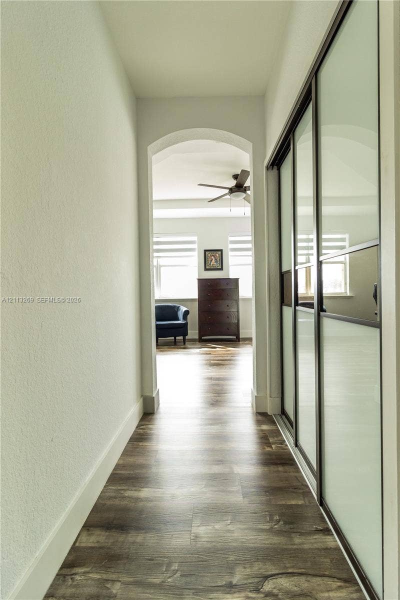 11494 NW 79th Lane, Doral, FL 33178 Arched pass-through featuring wood-finish flooring and floor-to-ceiling sliding closet doors with frosted glass panels