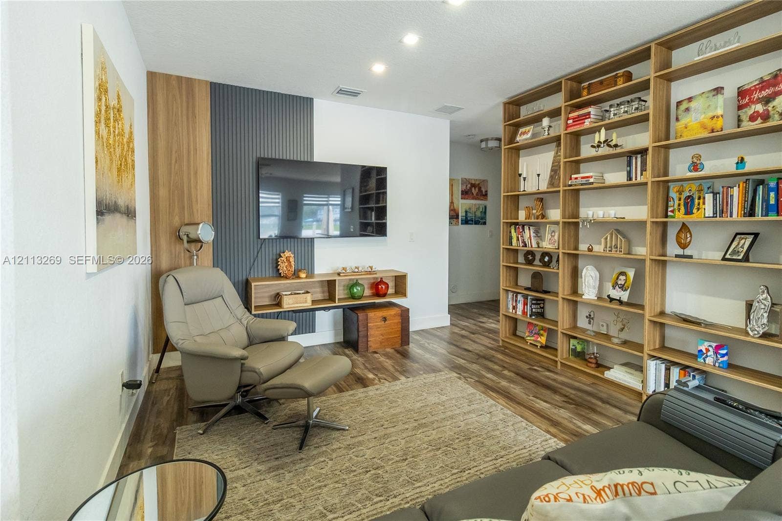 11494 NW 79th Lane, Doral, FL 33178 Custom floor-to-ceiling built-in shelving, wood-finish flooring, and a decorative accent wall featuring vertical slat paneling and wood trim