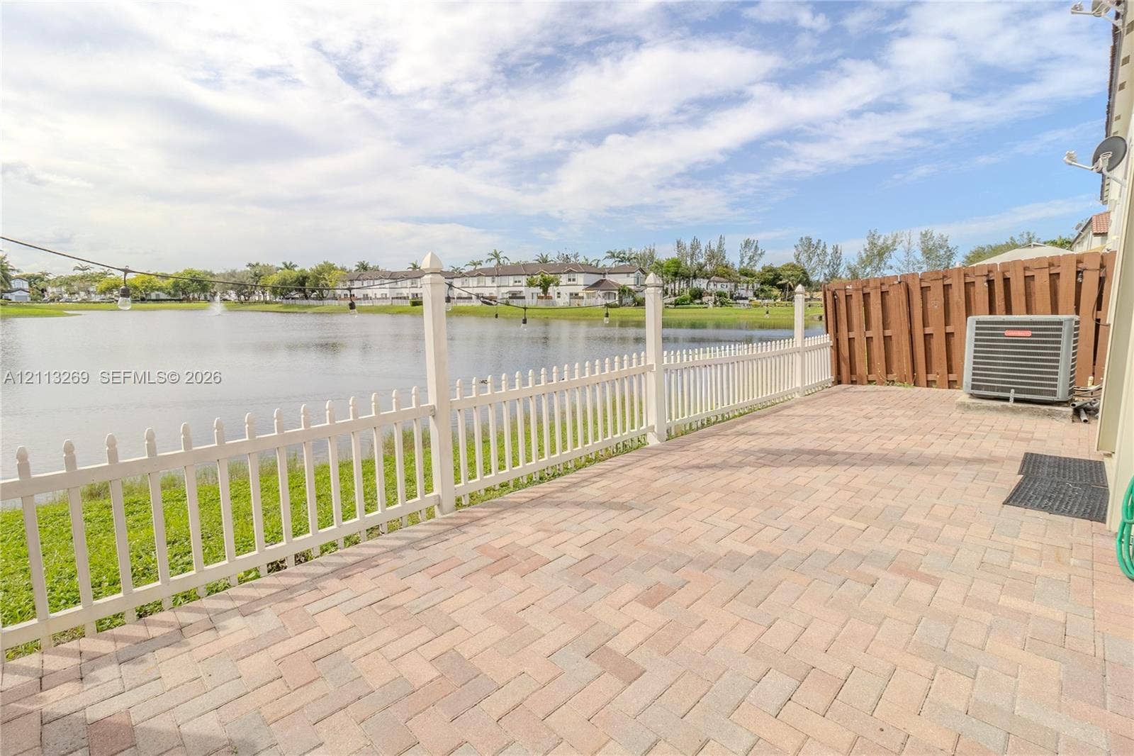 11494 NW 79th Lane, Doral, FL 33178 Paver patio with a white picket fence, overlooking a water feature