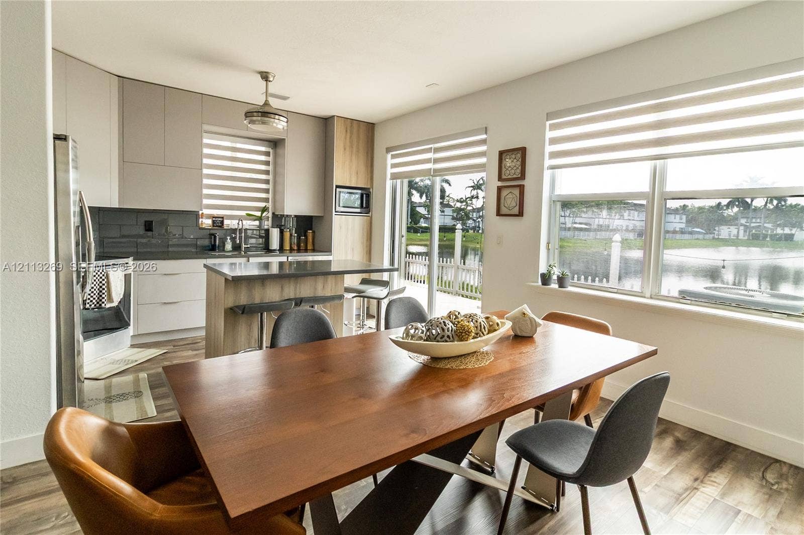 11494 NW 79th Lane, Doral, FL 33178 Kitchen featuring flat-panel cabinetry, a central island, wood-finish flooring, tiled backsplash, and large windows with integrated blinds