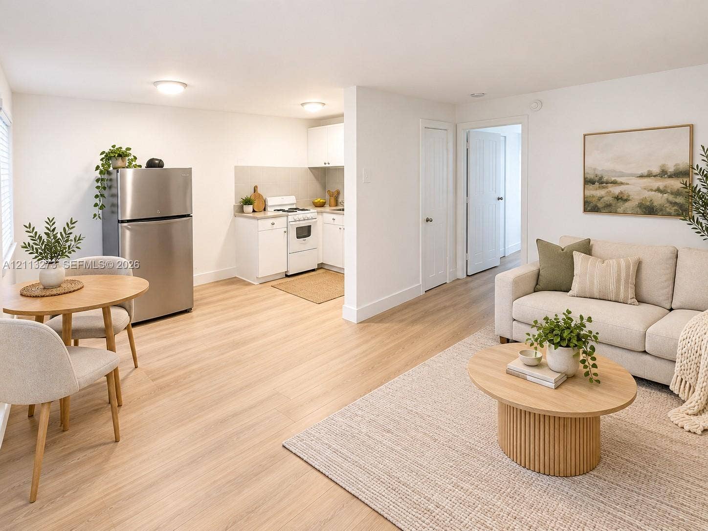 Kitchen area featuring white cabinetry, integrated stainless steel refrigerator, and wood-finish flooring throughout