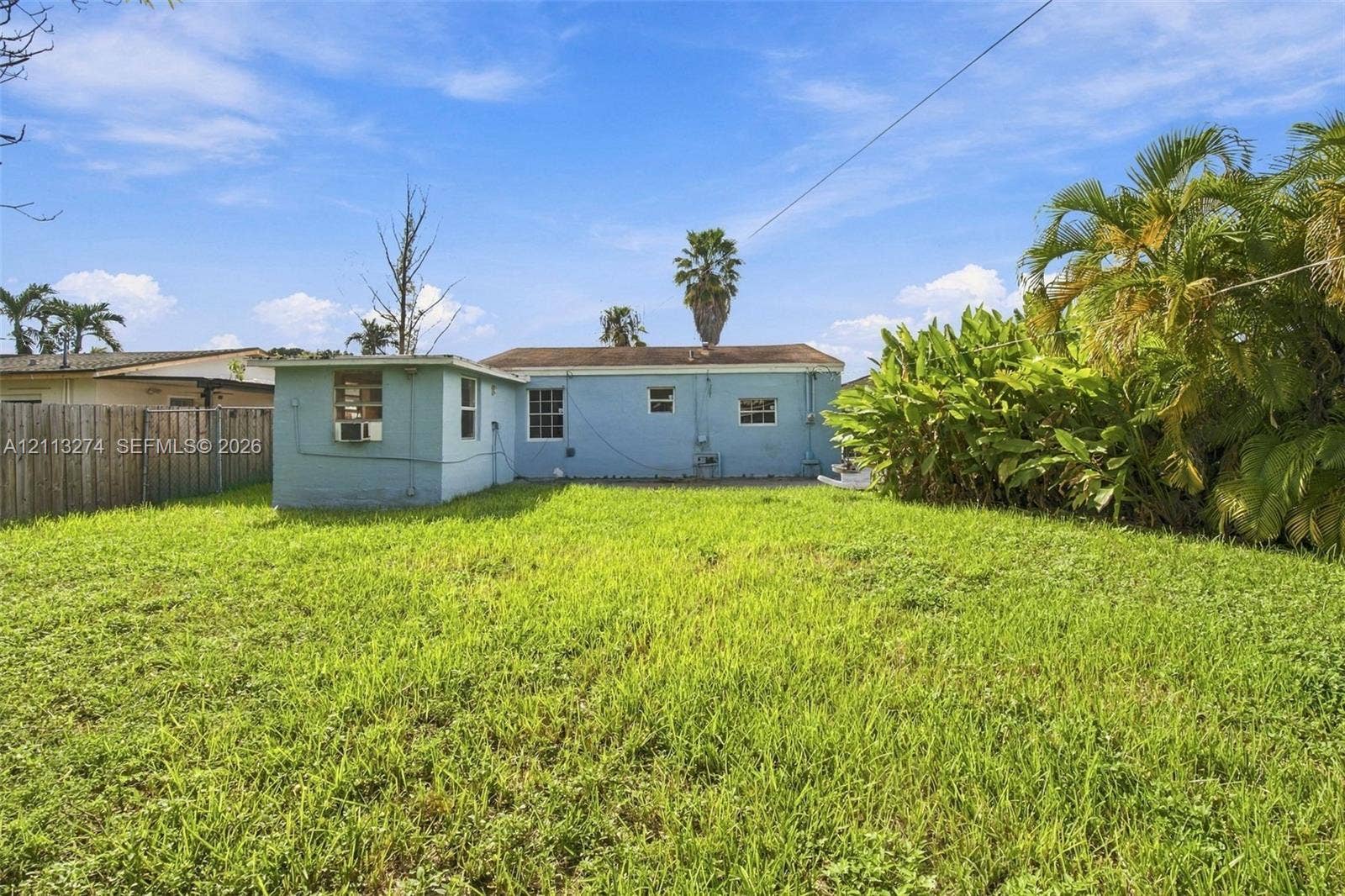 6521 SW 42nd Street, Miami, FL 33155 Expansive backyard featuring a grass lawn, perimeter wood fencing, and mature landscaping