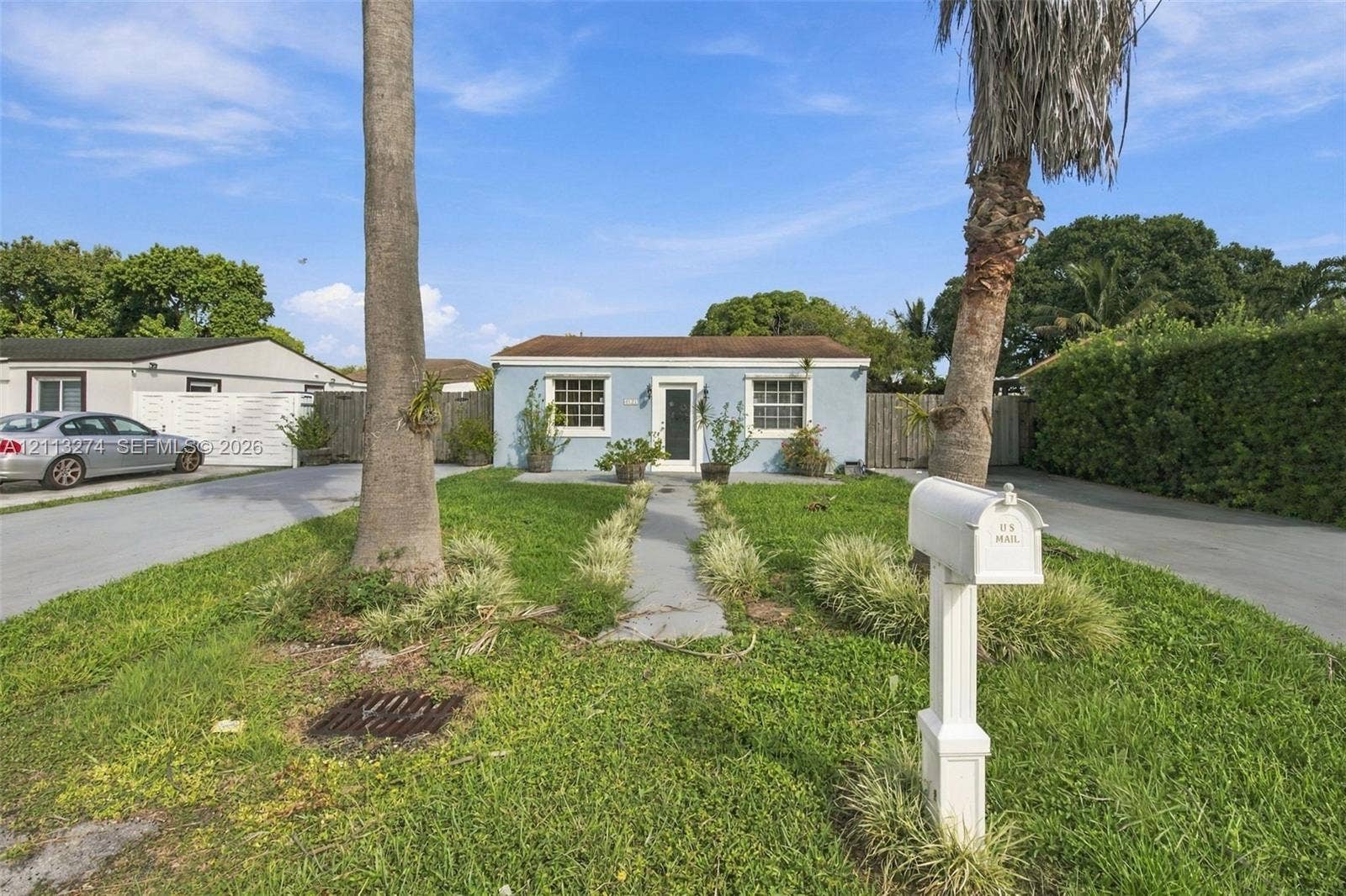 6521 SW 42nd Street, Miami, FL 33155 Single-story residence featuring a light blue stucco exterior, a pitched roofline, white-trimmed windows, and a central entryway