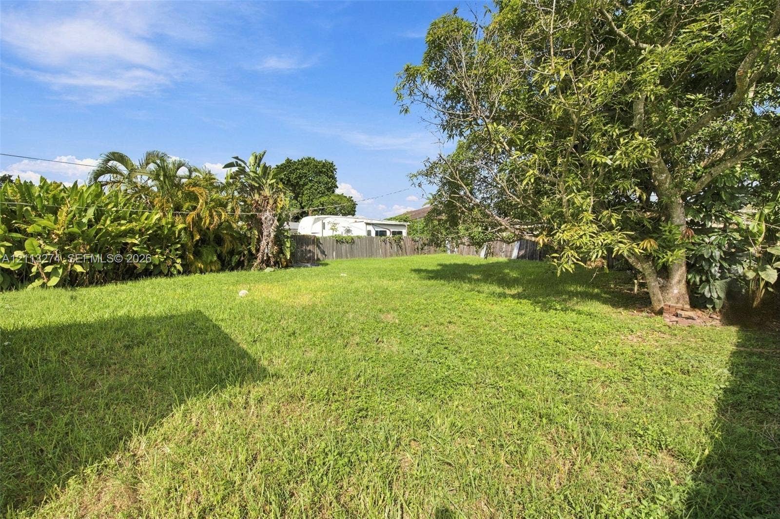 6521 SW 42nd Street, Miami, FL 33155 Expansive backyard featuring a lawn, perimeter wood fencing, and mature trees