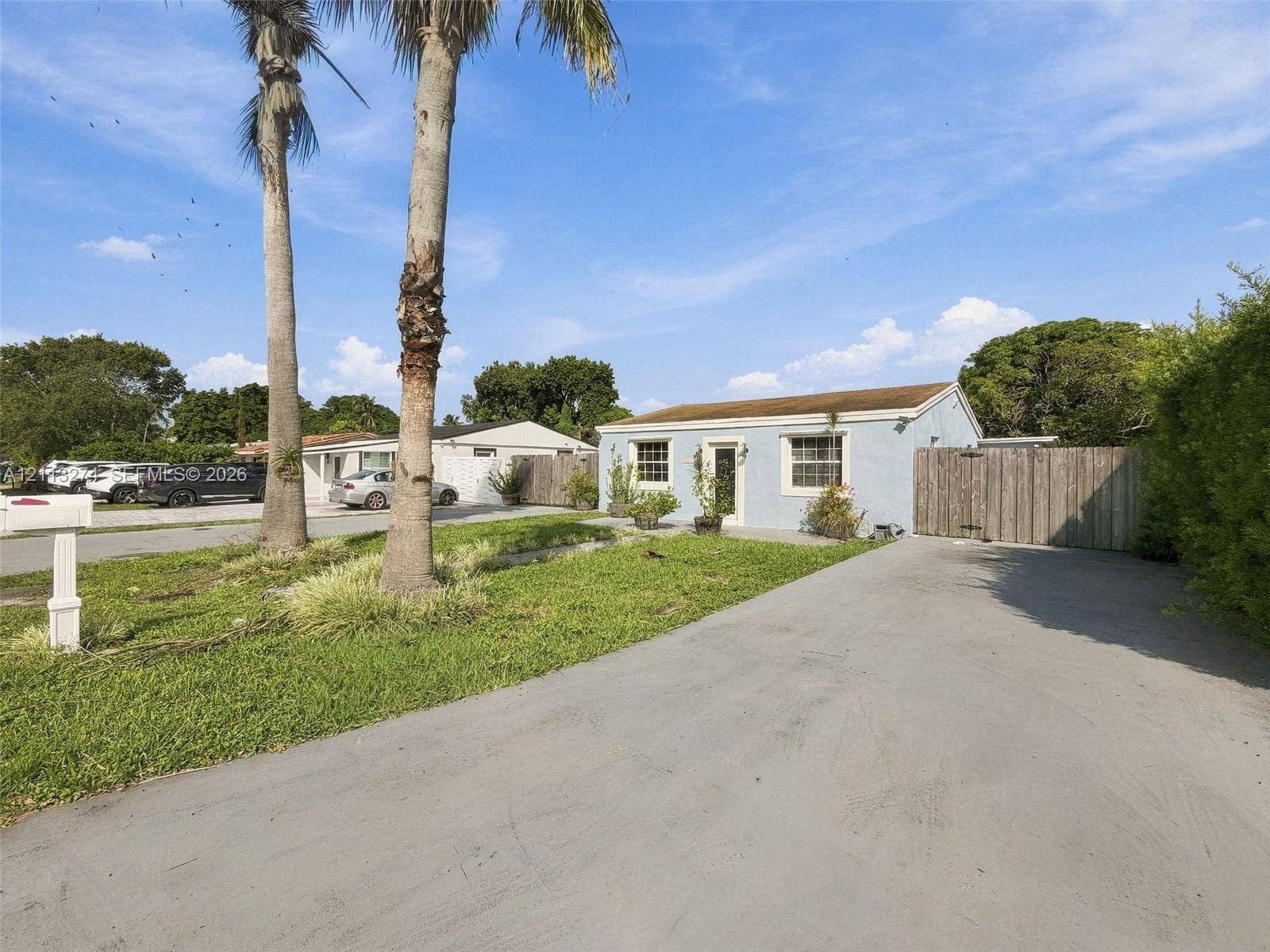 6521 SW 42nd Street, Miami, FL 33155 Exterior facade featuring light-toned stucco, multi-pane windows, paved driveway, and mature palm trees