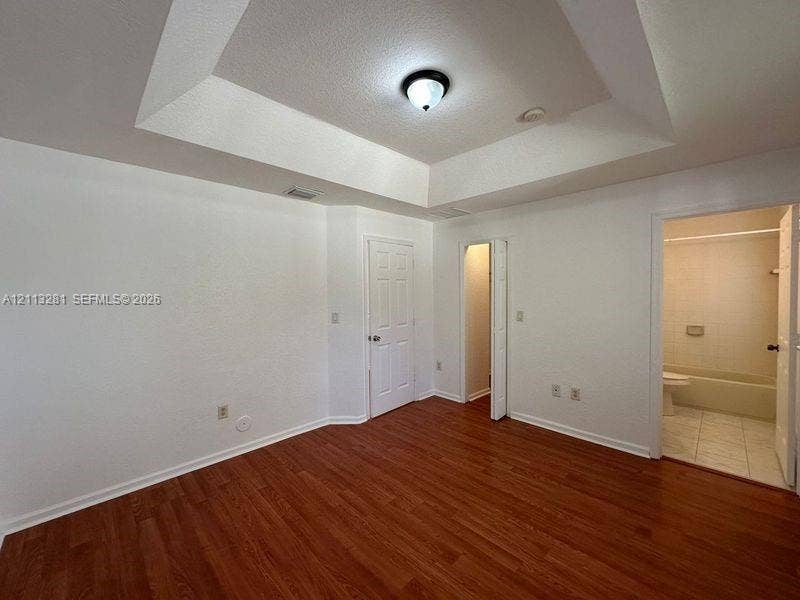 2615 SE 15th Place, #190, Homestead, FL 33035 Tray ceiling with central flush-mount lighting, wood-finish flooring, and multi-panel interior doors