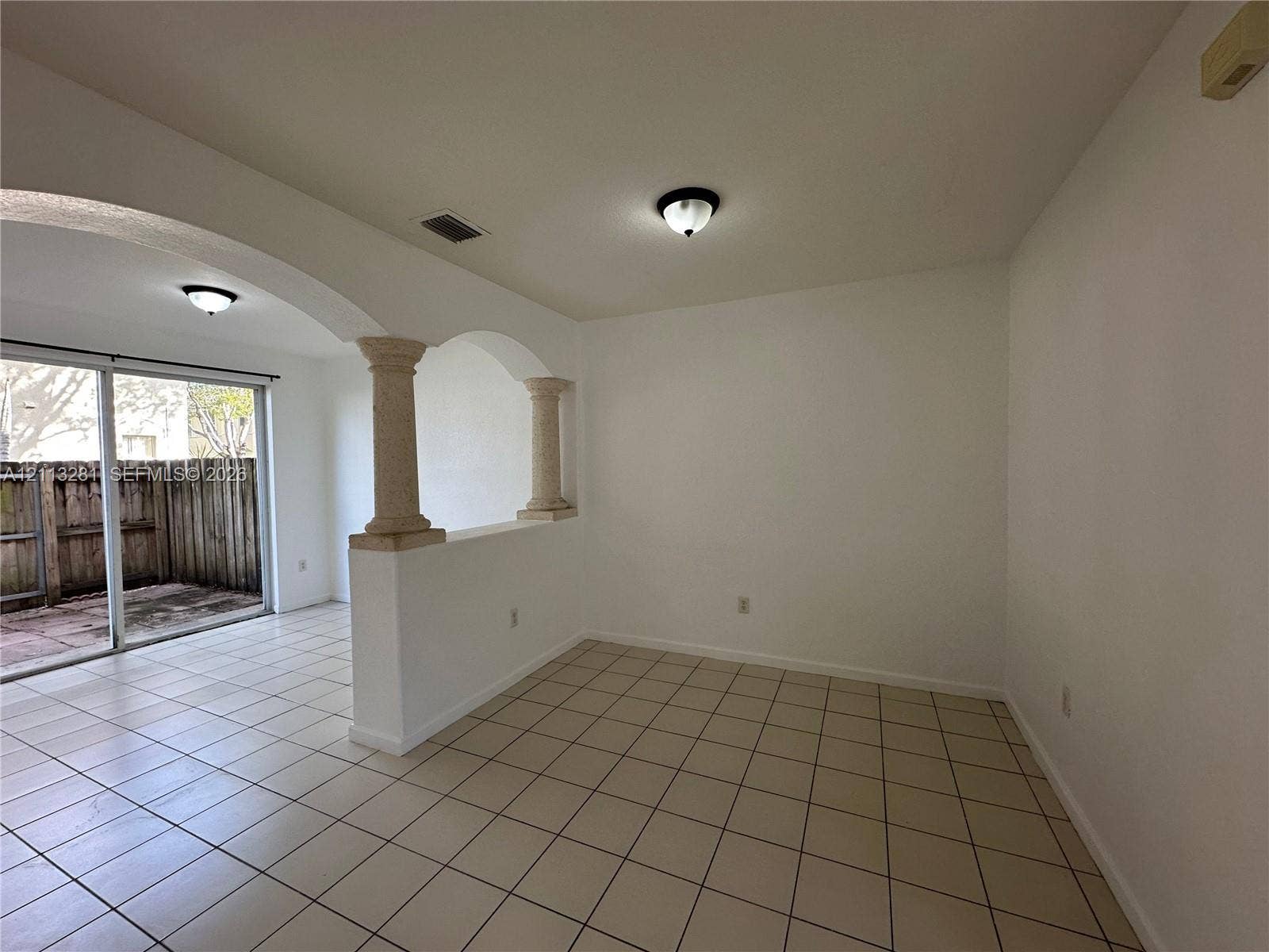 2615 SE 15th Place, #190, Homestead, FL 33035 Interior space featuring ceramic tile flooring, architectural archways with decorative pillars, and sliding glass doors
