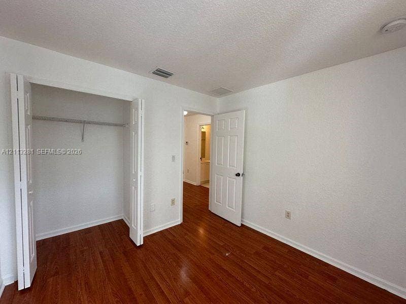 2615 SE 15th Place, #190, Homestead, FL 33035 Room featuring wood-finish flooring, a bi-fold door closet with built-in shelving, and a six-panel interior door